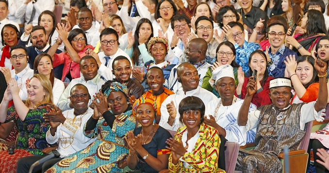 Des jeunes du monde entier applaudissent avec enthousiasme dans un auditorium.