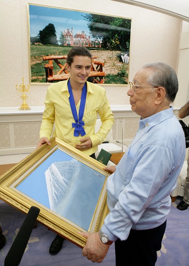 Daisaku Ikeda holding a large, framed photo of Mt. Fuji while showing it to Orlando Bloom.