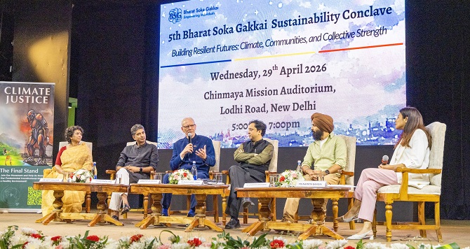 Six people sit on stage in front of a large audience.