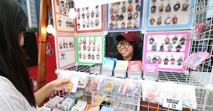 A woman serving a customer at a pop-up art booth.