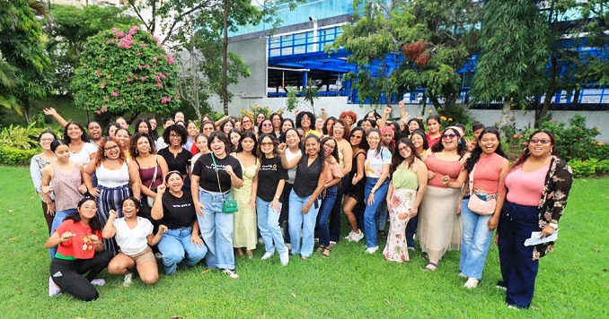 A group of women on a green lawn in a garden outside a building.