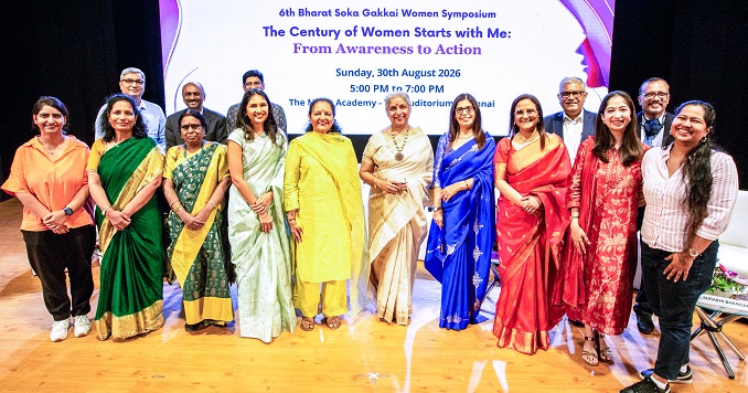 Participants of a large symposium stand on stage for a commemorative photo.