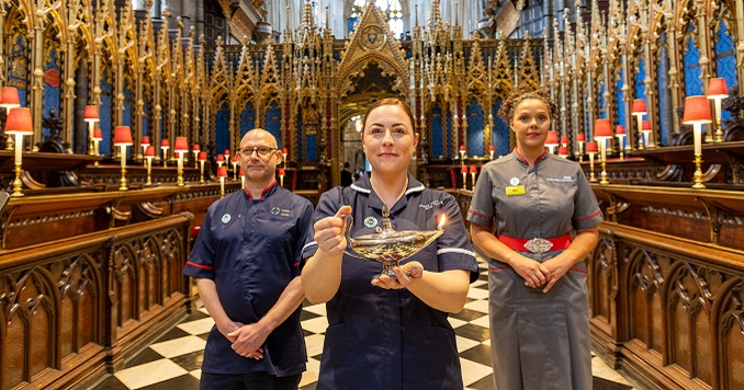 Three people in nurses’ uniforms standing in a cathedral for a ceremony.