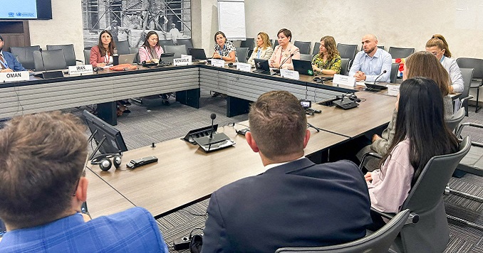 People seated at tables arranged in a square around the room.