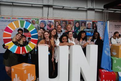 A diverse group of smiling young men and women pose with the UN Envoy on Youth