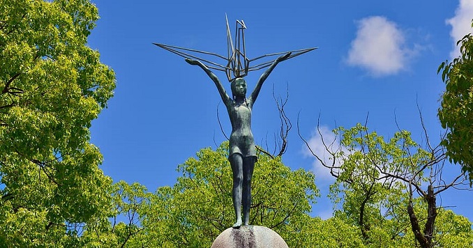 Statue of girl holding origami crane above her head