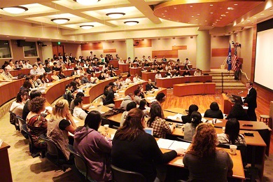 Jim Garrison hablando desde un podio en una sala de conferencias llena de gente