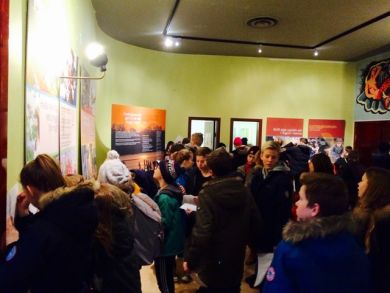 Several young people crowd around exhibition panels