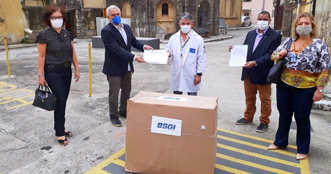 Cinco personas con máscaras al exterior de pie alrededor de una gran caja de carton