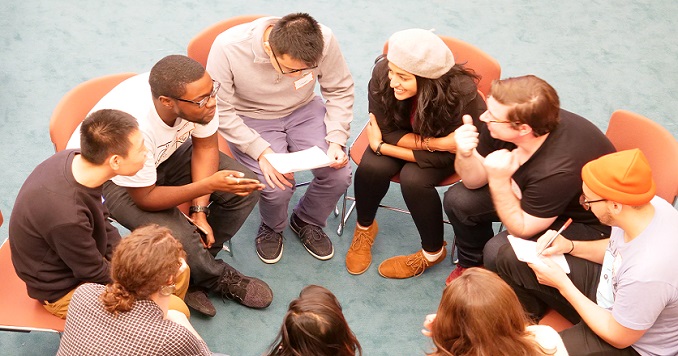 A group of young people seated in a close circle in discussion