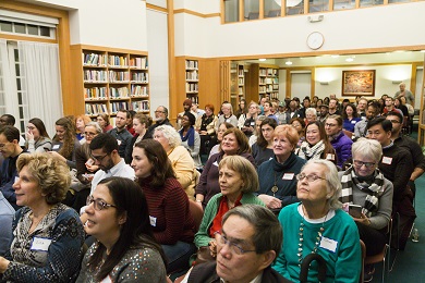 A diverse audience seated in a small hall.