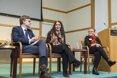 Three speakers seated on a stage