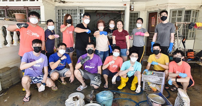 A group photo of men, women and youths outside a house.