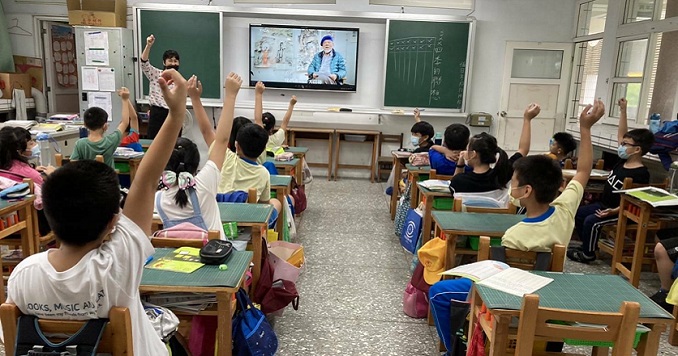 Estudiantes de la escuela primaria levantan la mano durante una presentación del Museo Itinerante de Arte 