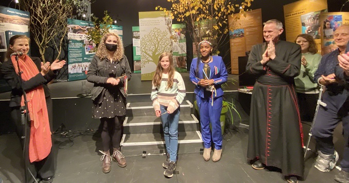 A group of people stand in front of exhibition panels in a hall