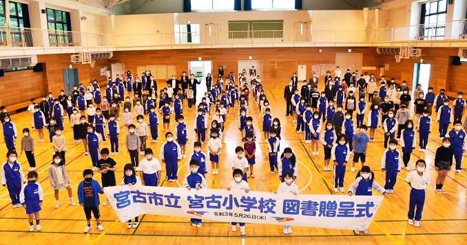School children lined up in a hall, with the front row holding a banner