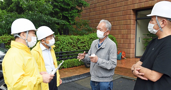 Un grupo de cuatro hombres con cascos y mascarillas conversan al aire libre