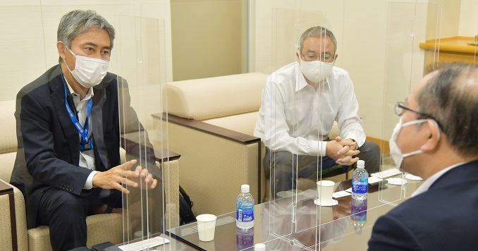 Three men in discussion across a low table