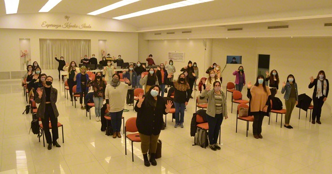 Several women standing in a hall and waving at the camera