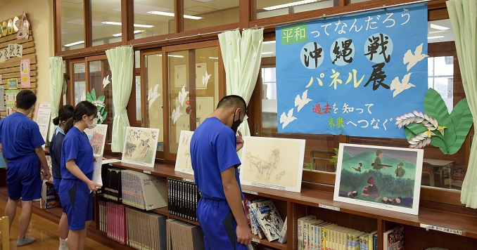 Young people looking at paintings displayed in a library