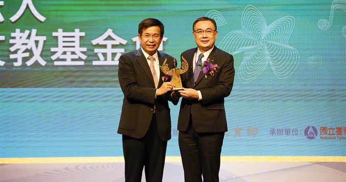 Dos hombres en un escenario exhiben un premio