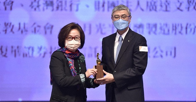 A man and women pose on stage with an award