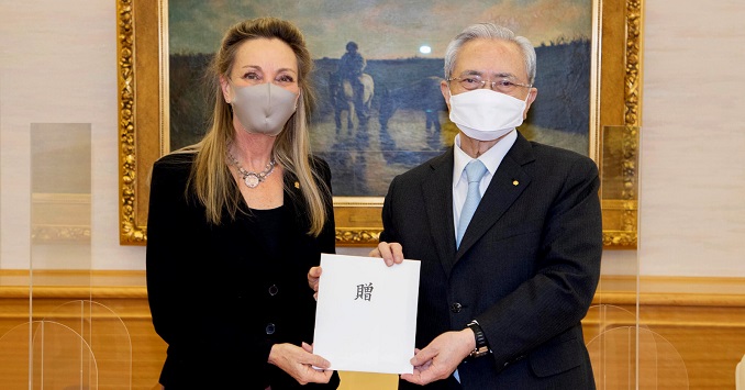 Two masked people in front of painting