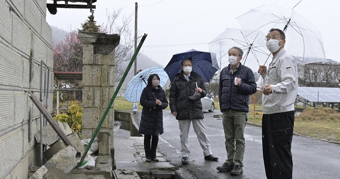 Four people looking at earthquake damage