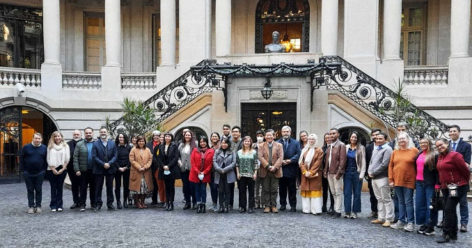 Personas de pie posan para una foto grupal frente a un edificio histórico