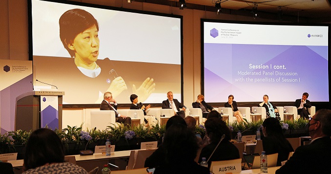 People sitting in a conference room with three big screens at the front