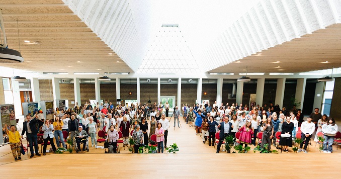 Large group of people standing for a celebratory photo in a hall