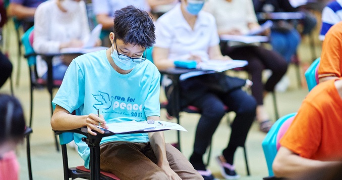 Personas sentadas que realizan un examen escrito en una gran sala