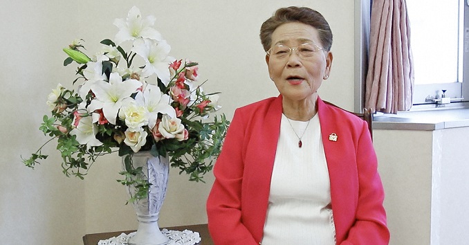 A woman seated next to a display of flowers