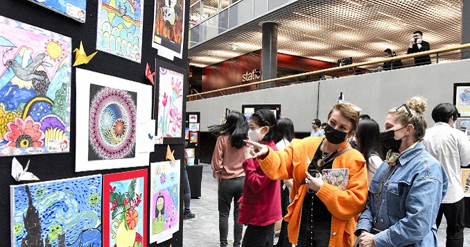 Personas observando una muestra de dibujos de niños