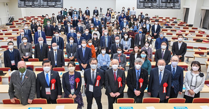 A large group of people posing for a commemorative photo in a lecture theater. 