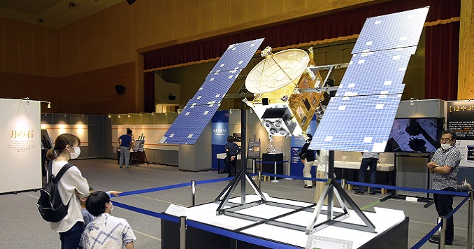 Visitantes de la exposición observando la réplica de un satélite.