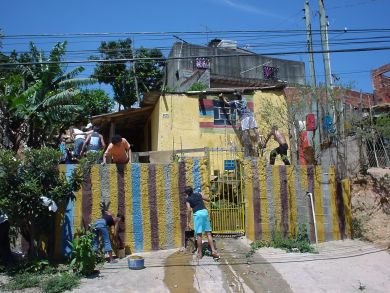 Ronaldo con unos jóvenes pintan de color una casa de la favela y su muro
