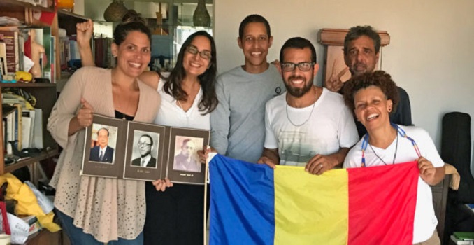 Group photo of six smiling men and women holding a Soka Gakkai flag