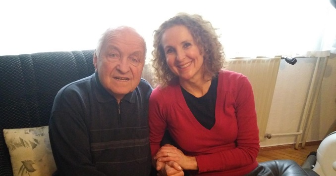 Anita sitting with her father, holding his hand tenderly