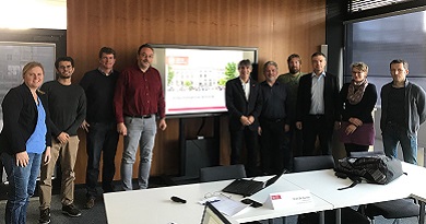 A group of ten men and women, members of the sustainability council, pose in front of a projection screen 