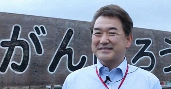 Foto de perfil de Kenichi posando frente al letrero