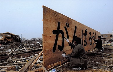 Two men painting letters onto a large wooden sign