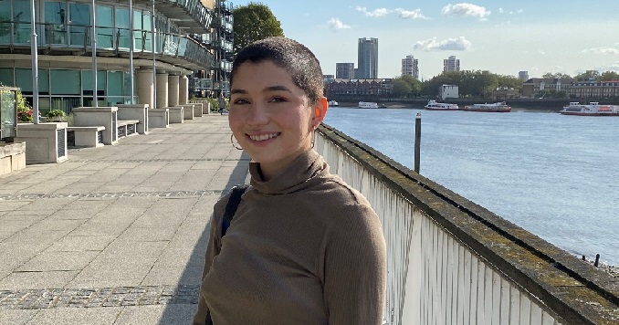 A smiling young woman standing on a waterfront