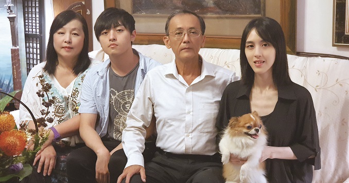 4个人坐在沙发上,其中1个人抱着狗。
