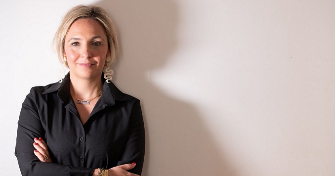 A smiling woman standing against a white wall  