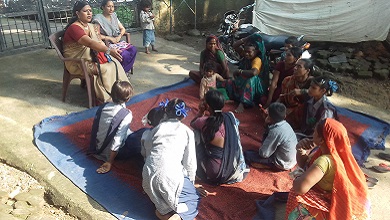 En el exterior, una mujer da clases a un grupo de personas sentadas en el suelo