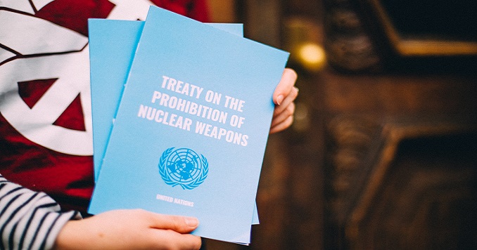 Hands holding copies of the Treaty on the Prohibition of Nuclear Weapons