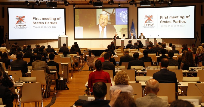 Personas sentadas en una sala de conferencias ven un discurso en vídeo